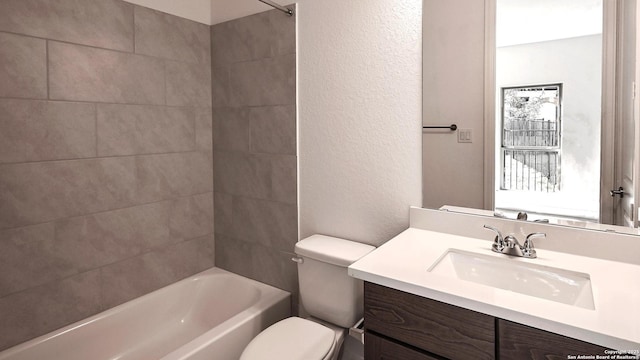 bathroom featuring a textured wall, shower / tub combination, vanity, and toilet