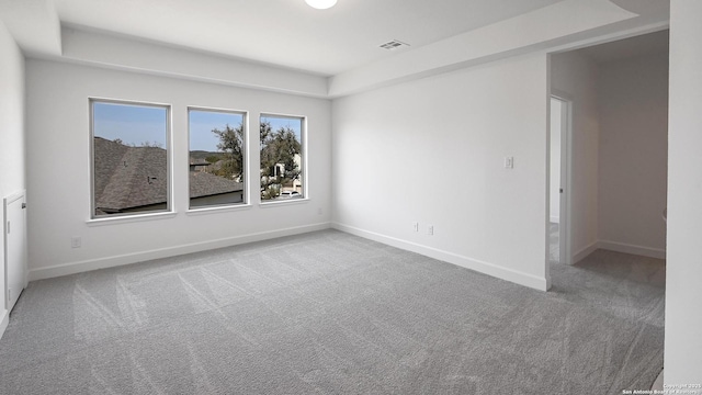 empty room featuring carpet, visible vents, and baseboards