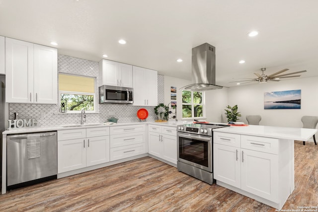 kitchen featuring kitchen peninsula, white cabinets, appliances with stainless steel finishes, and island range hood