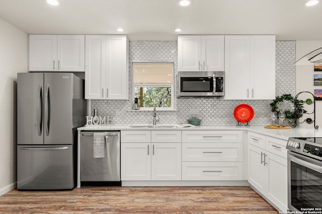 kitchen with appliances with stainless steel finishes, light wood-type flooring, and white cabinetry