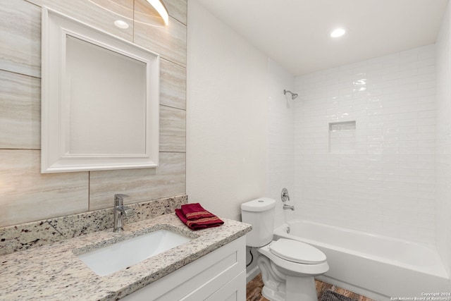 full bathroom featuring vanity, wood-type flooring, tiled shower / bath, tile walls, and toilet