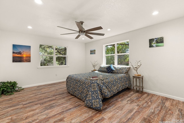 bedroom with dark hardwood / wood-style floors, multiple windows, and ceiling fan