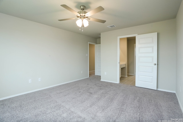 unfurnished bedroom with light carpet, ensuite bathroom, and ceiling fan