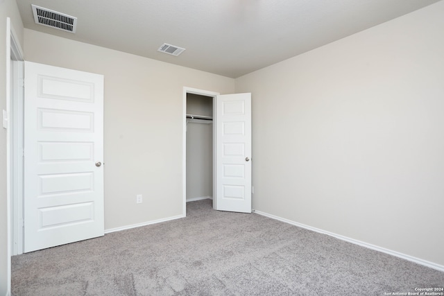 unfurnished bedroom with a closet and light colored carpet