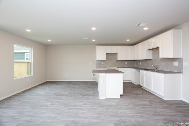 kitchen with white cabinets, light hardwood / wood-style flooring, sink, and a kitchen island