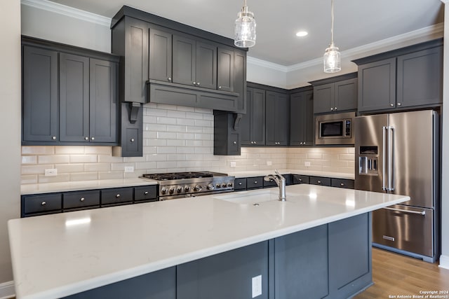 kitchen with a center island with sink, hanging light fixtures, premium appliances, ornamental molding, and backsplash