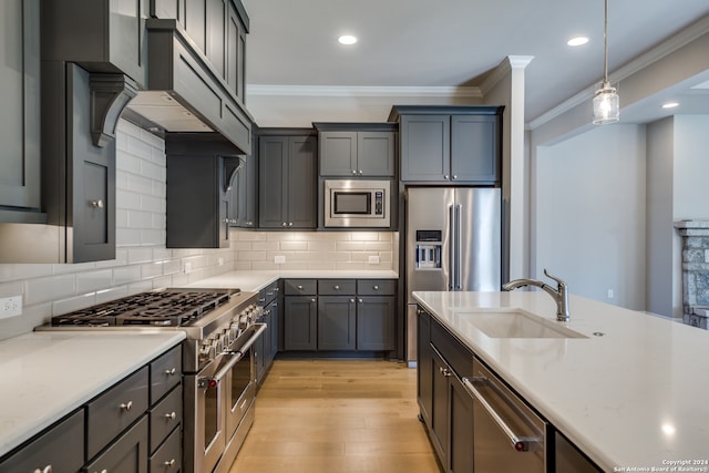 kitchen with pendant lighting, crown molding, sink, and premium appliances