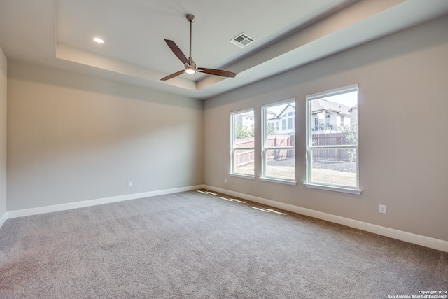 carpeted empty room with a raised ceiling and ceiling fan