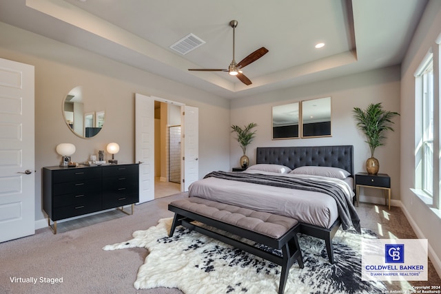 bedroom with light carpet, a raised ceiling, and ceiling fan