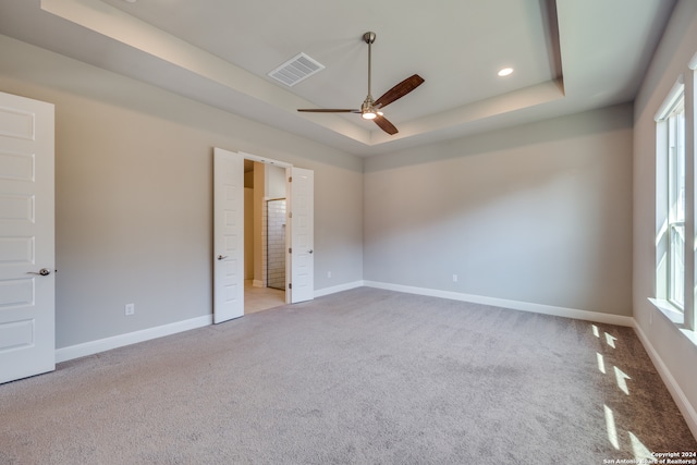 carpeted spare room featuring a raised ceiling and ceiling fan