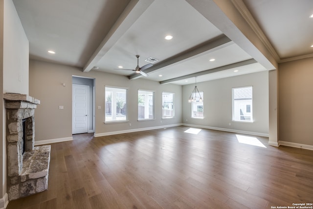 unfurnished living room featuring dark hardwood / wood-style floors, beam ceiling, ceiling fan with notable chandelier, and a stone fireplace