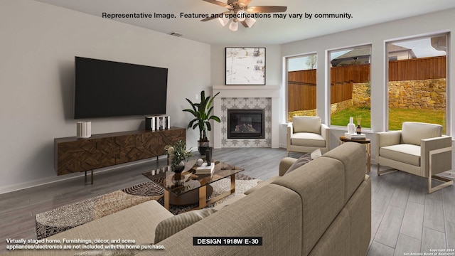 living room with ceiling fan, hardwood / wood-style flooring, and a tiled fireplace