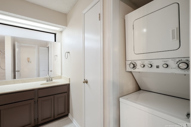 laundry area featuring sink, stacked washing maching and dryer, and a textured ceiling