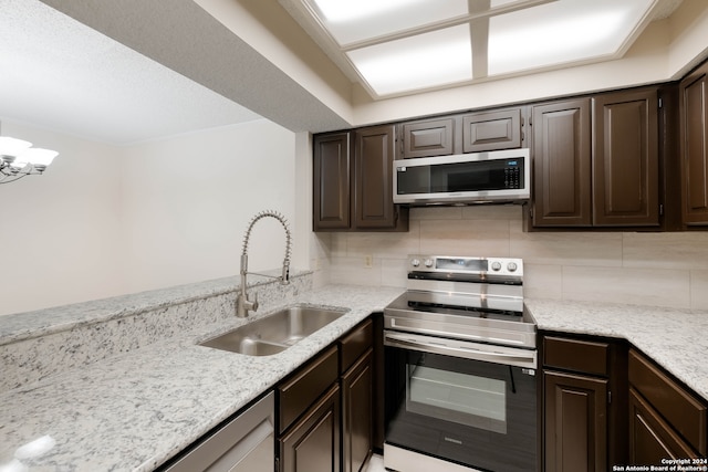 kitchen featuring tasteful backsplash, dark brown cabinetry, sink, light stone counters, and stainless steel appliances