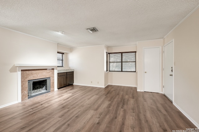 unfurnished living room with ornamental molding, hardwood / wood-style flooring, plenty of natural light, and a premium fireplace