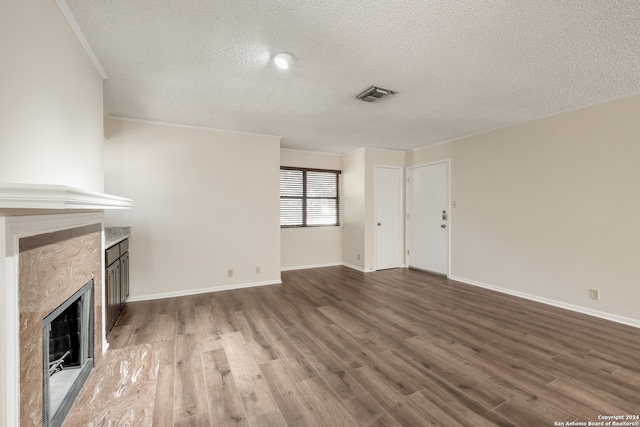 unfurnished living room with crown molding, hardwood / wood-style flooring, and a textured ceiling