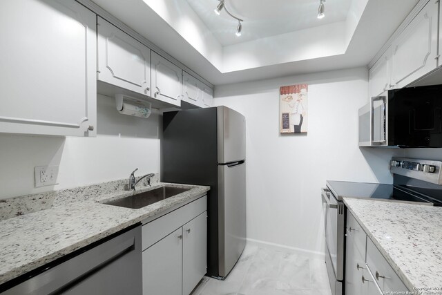 kitchen featuring stainless steel appliances, light stone countertops, sink, and white cabinetry