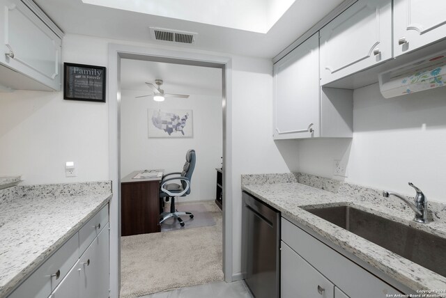 kitchen featuring light stone counters, ceiling fan, stainless steel dishwasher, white cabinets, and sink