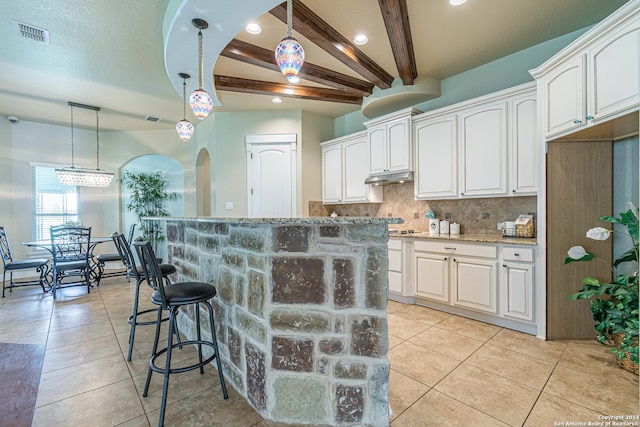 kitchen with beamed ceiling, a kitchen island, and white cabinetry