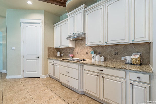 kitchen with light stone counters, backsplash, white cabinets, light tile patterned floors, and black electric stovetop