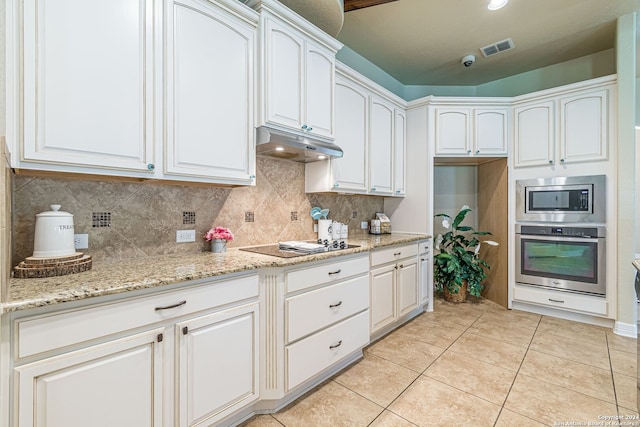 kitchen featuring stainless steel appliances, light stone counters, light tile patterned floors, and white cabinetry