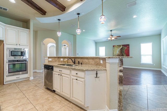 kitchen featuring sink, white cabinetry, hanging light fixtures, appliances with stainless steel finishes, and a center island with sink