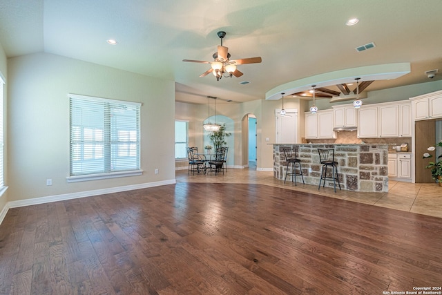 unfurnished living room featuring ceiling fan, light wood-type flooring, and vaulted ceiling