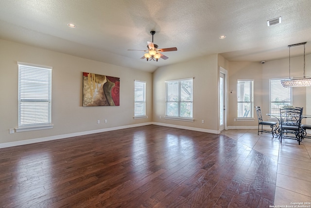 unfurnished living room featuring ceiling fan, dark hardwood / wood-style floors, and a textured ceiling