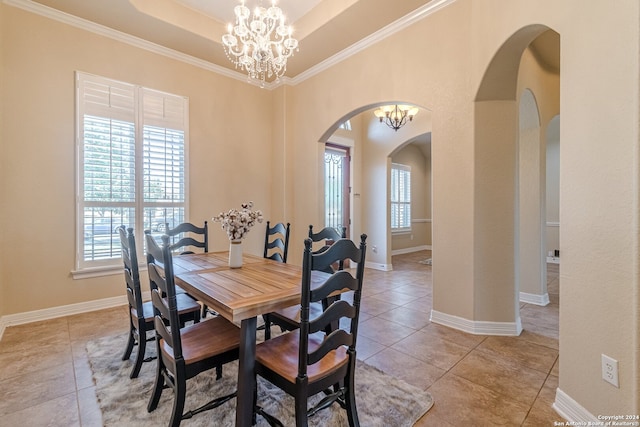 dining space with crown molding, a tray ceiling, tile patterned floors, and a chandelier