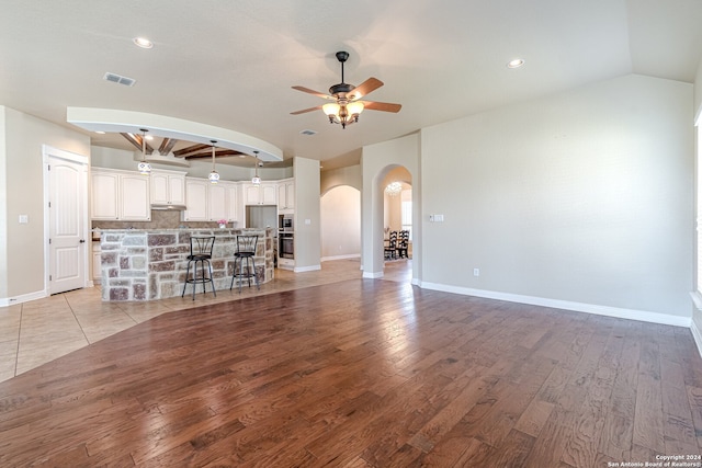 unfurnished living room with ceiling fan, light hardwood / wood-style flooring, and lofted ceiling