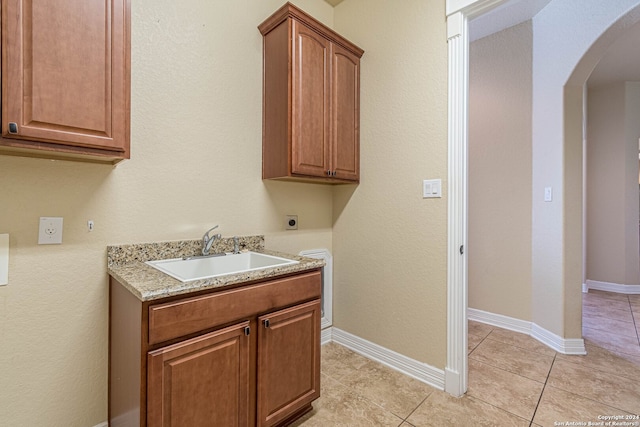 laundry room featuring light tile patterned flooring, hookup for an electric dryer, sink, and cabinets