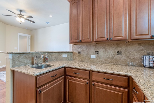 kitchen featuring hardwood / wood-style flooring, light stone countertops, sink, and kitchen peninsula