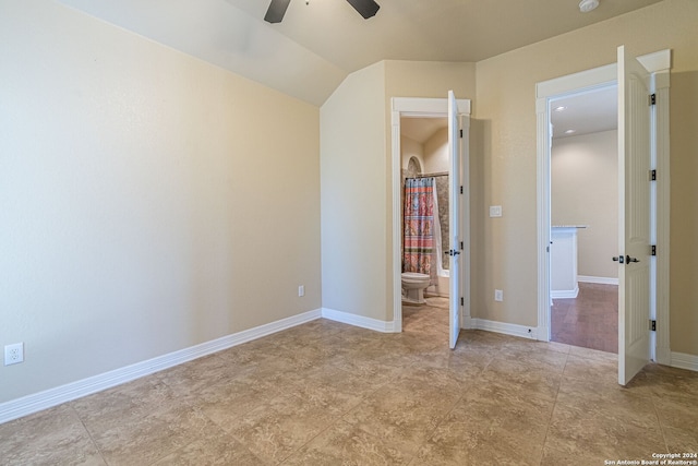 unfurnished bedroom with vaulted ceiling, ceiling fan, and connected bathroom