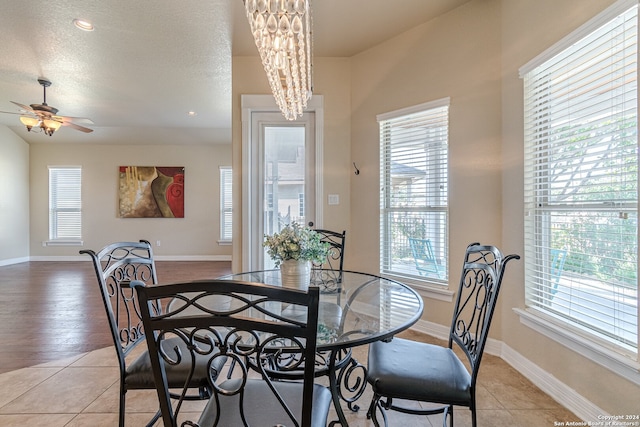 dining area featuring ceiling fan with notable chandelier, light wood-type flooring, plenty of natural light, and a textured ceiling