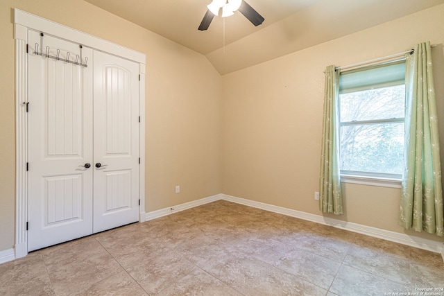 unfurnished bedroom featuring lofted ceiling, a closet, light tile patterned floors, and ceiling fan