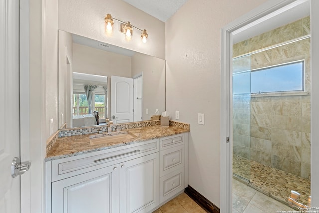 bathroom featuring vanity, tiled shower, tile patterned flooring, and a wealth of natural light