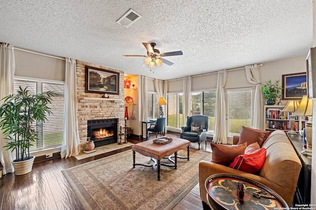 living room with a brick fireplace, ceiling fan, hardwood / wood-style floors, and a textured ceiling