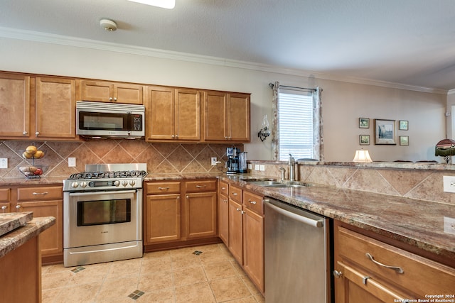 kitchen with sink, stone countertops, appliances with stainless steel finishes, crown molding, and decorative backsplash