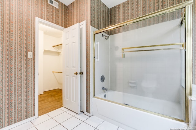 bathroom featuring tile patterned flooring and bath / shower combo with glass door