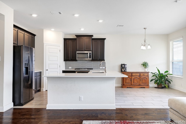 kitchen featuring a kitchen island with sink, stainless steel appliances, light wood-type flooring, and sink