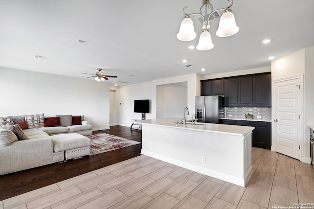 kitchen with an island with sink, sink, hanging light fixtures, light hardwood / wood-style flooring, and stainless steel refrigerator with ice dispenser