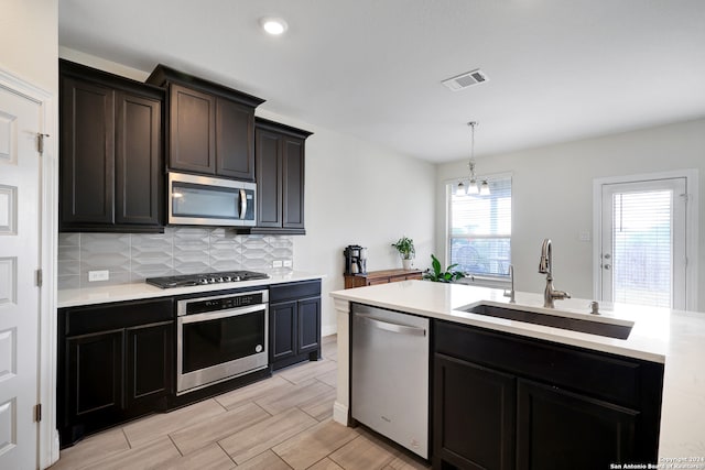 kitchen with light hardwood / wood-style floors, an inviting chandelier, sink, stainless steel appliances, and hanging light fixtures