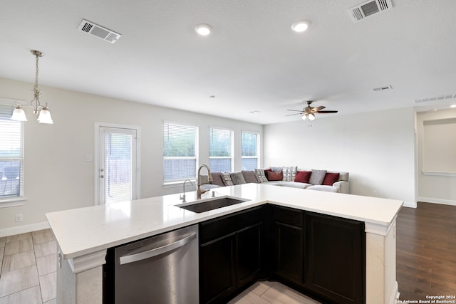 kitchen with light wood-type flooring, pendant lighting, sink, an island with sink, and stainless steel dishwasher