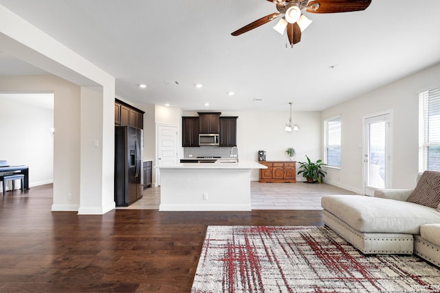 living room with ceiling fan with notable chandelier and hardwood / wood-style floors