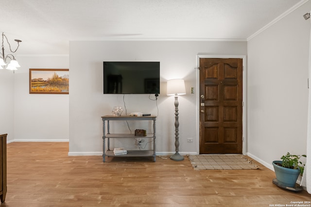 foyer with ornamental molding, an inviting chandelier, and light hardwood / wood-style floors