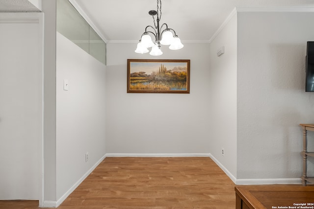 unfurnished dining area with hardwood / wood-style flooring, ornamental molding, and a notable chandelier