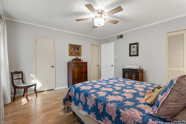 bedroom with light hardwood / wood-style floors, ornamental molding, ceiling fan, a textured ceiling, and a closet