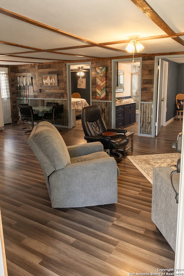 living room with wood walls, sink, dark hardwood / wood-style flooring, and a textured ceiling