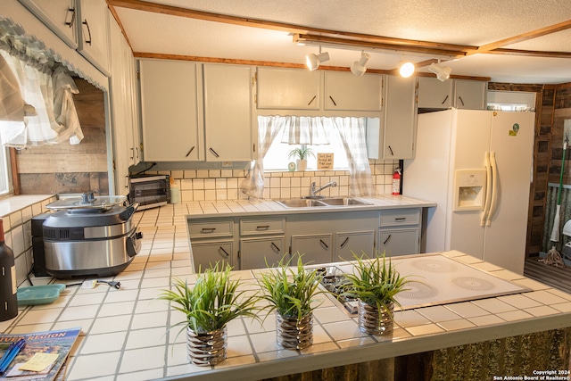 kitchen with white refrigerator with ice dispenser, sink, tile counters, and a textured ceiling