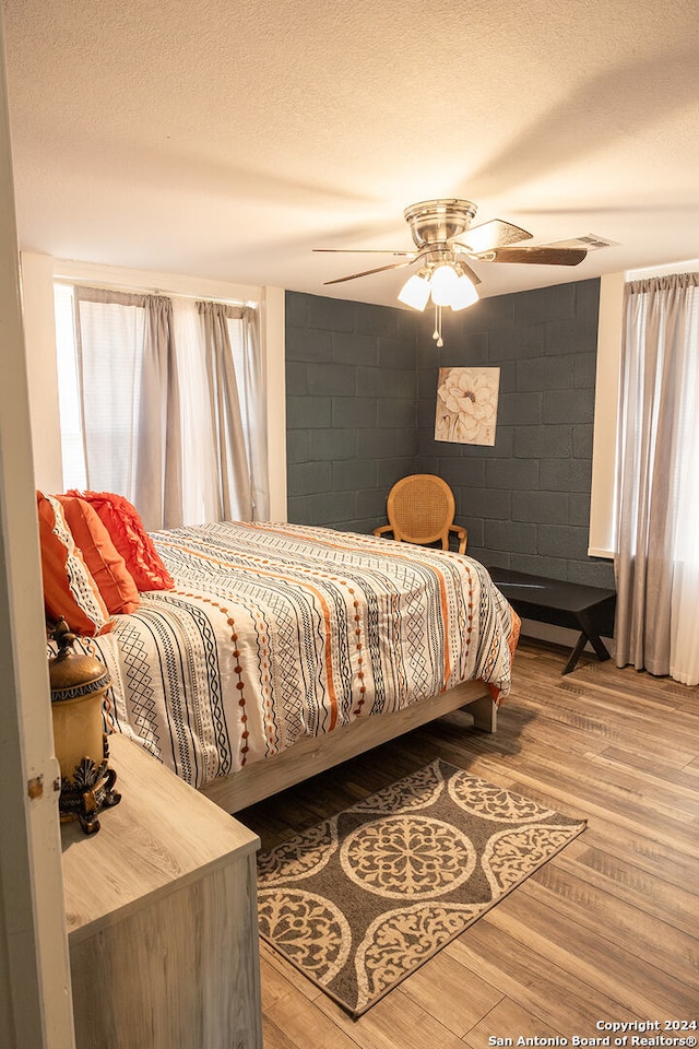 bedroom with ceiling fan, a textured ceiling, and hardwood / wood-style floors